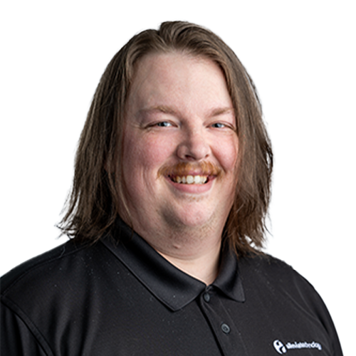AndrewH_CutOut An IT expert with long hair and a mustache smiling while managing and maintaining your network and IT investments.