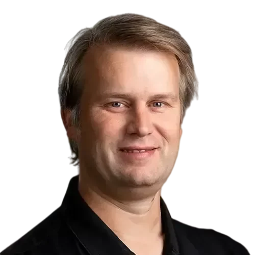 Daniel_web2-transformed A man in a black shirt smiling while managing and maintaining IT investments.