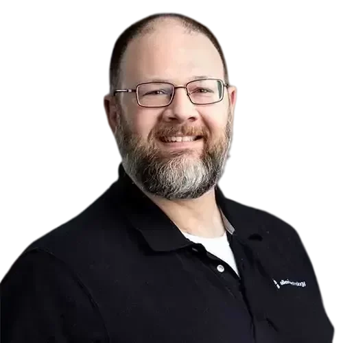 An IT expert with glasses and a beard smiling for the camera.