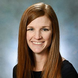 A woman with long red hair smiling for the camera.