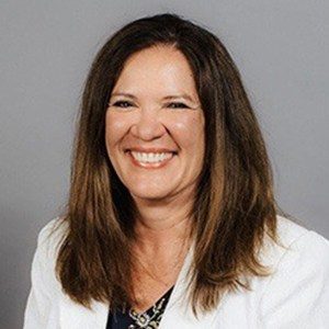 Sheila Rust A woman in a white blazer smiling.