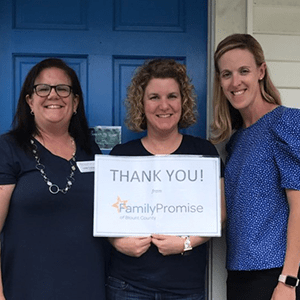Three women standing in front of a door with a sign that says thank you family promise.